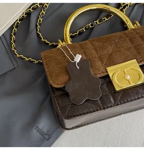 Detailansicht der retro gesteppten Wildleder Handtasche mit goldenem Griff und Kette.