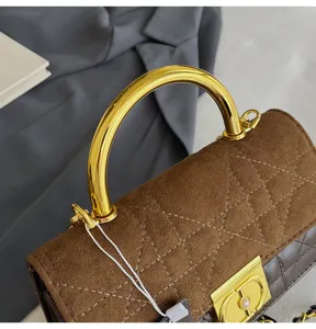Nahaufnahme der braunen gesteppten Handtasche mit luxuriösem goldfarbenem Metallgriff.