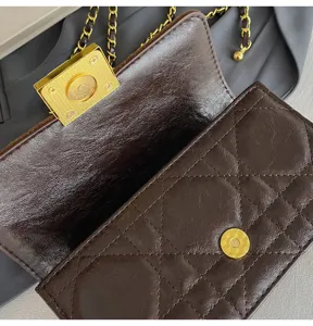 Nahaufnahme einer braunen gesteppten Ledertasche mit goldenen Metalldetails und Kette.