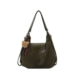 Detail view of dark green suede hobo bag with cute bear pendant and flap closure.