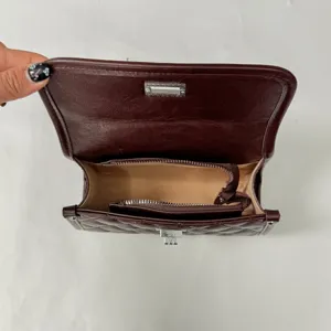 Detailed interior view of the dark brown quilted flap shoulder bag, showing storage.
