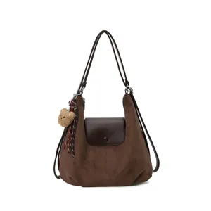 Brown suede shoulder bag detail showing front flap, double straps and cute teddy bear charm