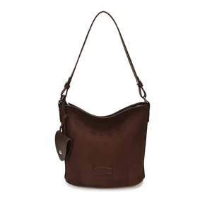 Detailed view of dark brown suede shoulder bag featuring a chic bucket shape and hanging charm.
