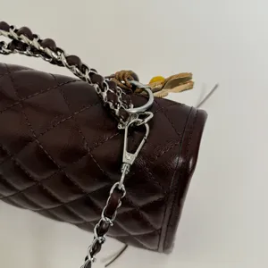 Dark brown quilted leather handbag detail featuring interwoven chain strap and silver hardware.