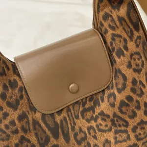 Leopard print shoulder bag detail featuring a brown leather snap flap and premium textured fabric.