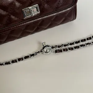 Dark brown quilted leather crossbody bag with silver hardware and chic chain strap detail.