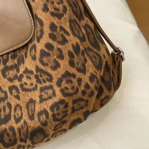 Close-up detail of a chic leopard print shoulder handbag with brown leather panel and strap.