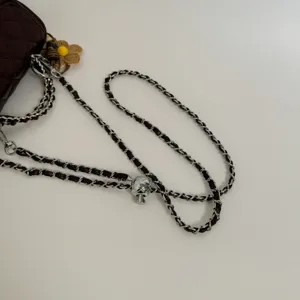 Detailed view of quilted leather shoulder bag with interwoven chain strap and metal ball.