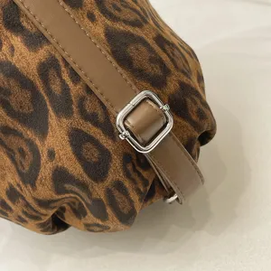 Leopard print bag strap detail, brown leather strap with silver metal buckle, soft texture.