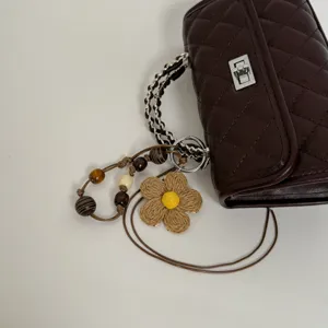 Dark brown quilted shoulder bag with chain handle, metal lock and woven flower charm.