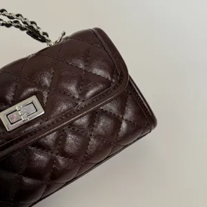 Close-up detail of dark brown quilted leather chain shoulder bag with classic turn-lock.