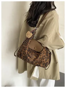 Stylish leopard print shoulder bag with plush bear charm, perfect for daily commuting.