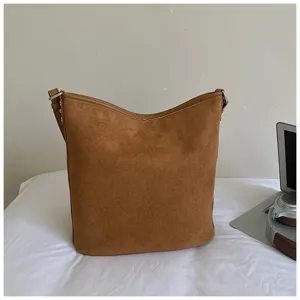Brown suede bucket bag detail shot, soft texture and minimalist shoulder strap design.