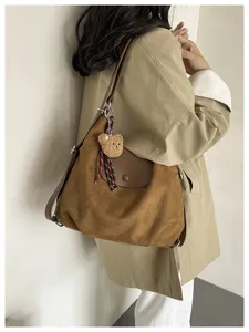 Brown suede slouchy shoulder bag detail, stylish commuter hobo bag with cute bear pendant.