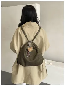 Stylish olive green shoulder backpack with flap design and cute bear charm for women.