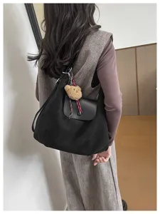 Fashion minimalist black shoulder bag with leather flap and cute teddy bear charm for women.