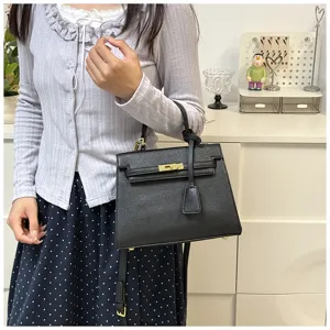 Schwarze Handtasche aus Kunstleder im Detail, elegante Trapezform mit goldener Hardware.