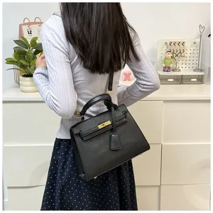 Lifestyle-Detailaufnahme einer klassischen schwarzen Lederschultertasche im Innenbereich.
