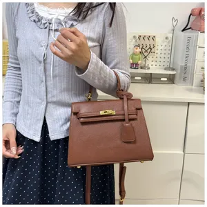 Detailansicht der braunen Handtasche aus Leder mit edlem Metallverschluss und Griff.