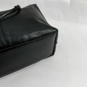 Close up view of the black leather handbag bottom detail, showing fine stitching and texture.