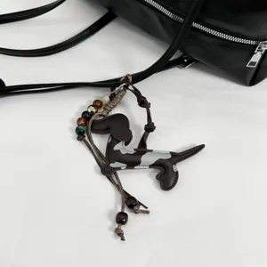 Detail of chic leather dachshund bag charm accessorizing a stylish black Boston handbag.