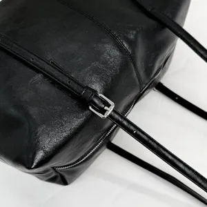 Black leather Boston bag detail, featuring durable silver hardware buckle and fine stitching texture.