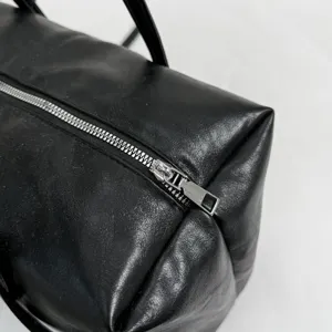 Close-up detail shot of black leather boston handbag zipper and texture, premium design.