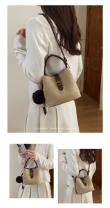 Dettaglio della borsa a secchiello in camoscio rétro con manico intrecciato e pompon chic.