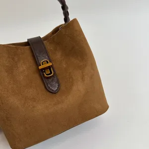 Primo piano borsa secchiello camoscio marrone, chiusura metallo vintage, elegante accessorio