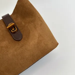 Primo piano dettagliato della borsa in camoscio marrone con cinturino e serratura.