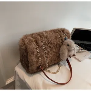 Gros plan détaillé du sac bandoulière en peluche marron montrant sa texture douce et sa chaîne.