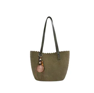Elegant woven shoulder bag with chic scalloped edge and stylish decorative charm pendant.