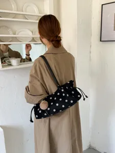 Detailed view of the chic black polka dot shoulder bag with cute pom-pom and drawstring.