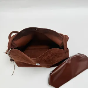 Detailed view of a brown suede shoulder bag showing its spacious interior and matching pouch.