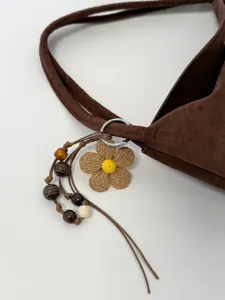 Brown suede shoulder bag detail, featuring cute woven flower charm and wooden beads.