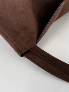 Brown suede shoulder bag detail showcasing fine stitching, premium texture and strap construction.