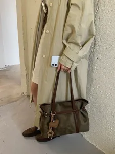 Detailansicht der Vintage-Wildleder-Tasche mit braunem Lederriemen und gestricktem Herz-Anhänger.