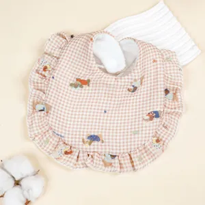 Nahaufnahme Detailansicht des Baby-Lätzchens aus Baumwollgaze mit Karomuster und Rüschen.