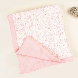 Detailed view of soft cotton baby blanket with floral pattern and pink gauze border.