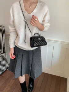 Detail shot of the black quilted chain crossbody bag styled with a white sweater and skirt.