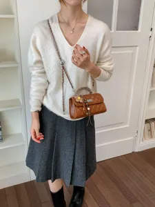 Elegant brown quilted chain crossbody bag paired with chic knit sweater and skirt look.