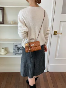 Retro brown quilted small crossbody bag with chain strap and cute flower charm detail.