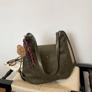 Green suede shoulder bag with leather flap and cute bear pendant for women commuting.