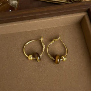 Nahaufnahme von Vintage-Gold-Creolen mit natürlichen Tigerauge-Perlen und Metallstruktur-Kugeln.