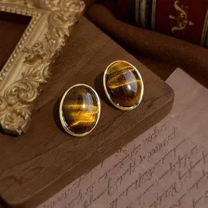 Elegante vintage ohrringe mit natur tigerauge stein und goldrand im retro stil detail