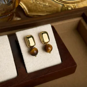 Detailansicht retro geometrischer Goldohrringe mit natürlichen braunen Tigerauge Perlen.