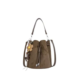 Detailansicht der braunen Wildleder-Beuteltasche mit Kordelzug und floralem Anhänger.