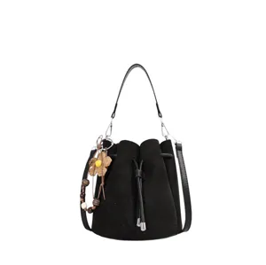 Detailansicht einer schwarzen Wildleder-Eimer-Tasche mit Kordelzug und Blumen-Anhänger.