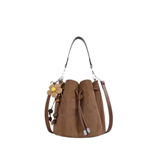 Braune Wildleder Beuteltasche Detailansicht mit Blumen Anhänger für modischen Retro Stil.