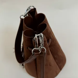 Nahaufnahme Detail der braunen Wildleder Beuteltasche mit silberner Hardware und Gurt.